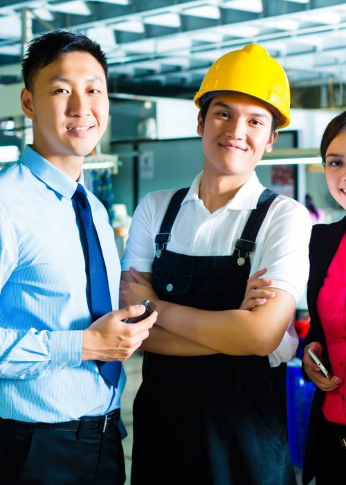 Chinese Shift supervisor or foreman, together with the owner or CEO and the Manager, standing proud in a factory